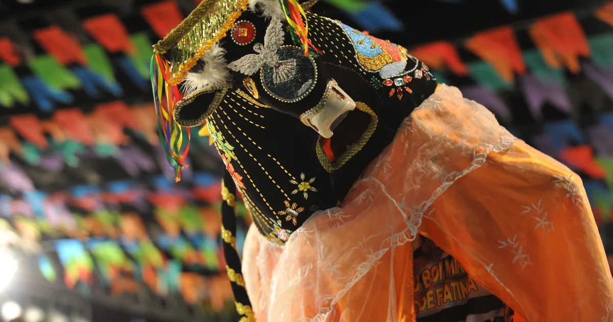 Indumentária bordada do Bumba Meu Boi do Maranhão sob bandeirolas de festa junina