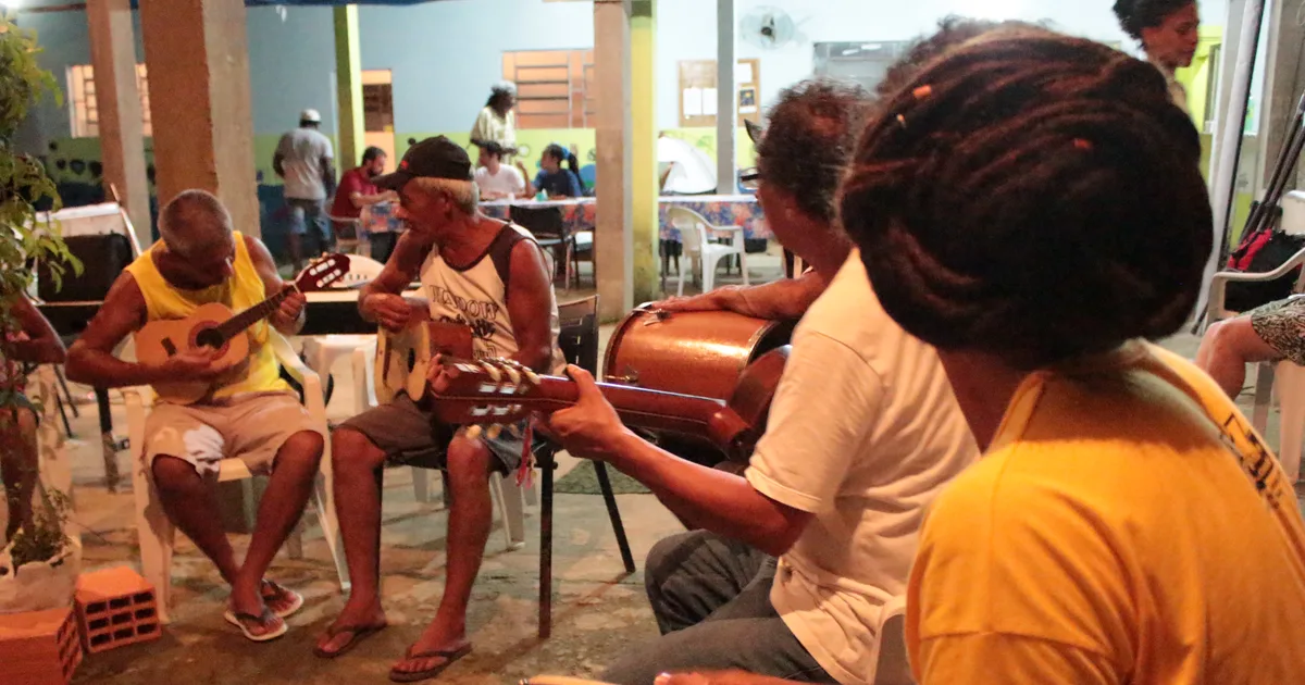 Músicos tocando viola e instrumentos do fandango caiçara reunidos em roda